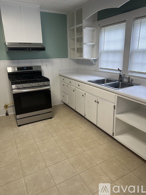 A kitchen with a black stove top oven and white cabinets.