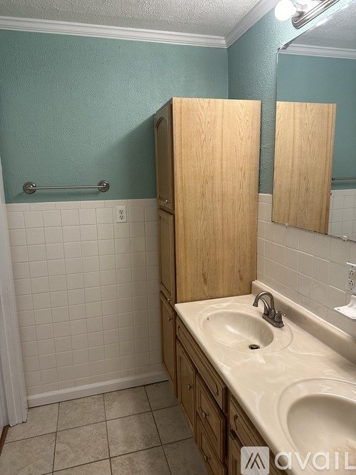 A bathroom with a sink and a wooden cabinet.