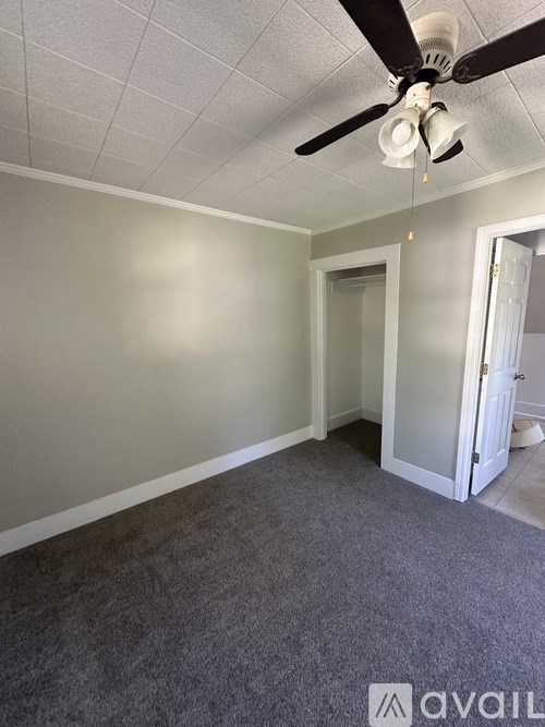 A room with a ceiling fan and carpeted floor.