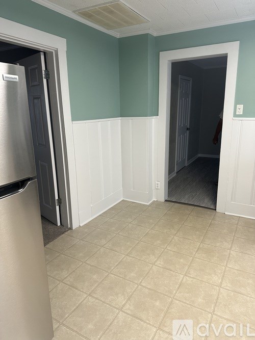 A kitchen with a refrigerator and a doorway leading to another room.
