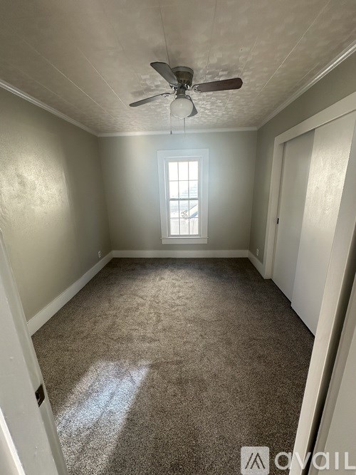 A room with a ceiling fan and carpeted floor.