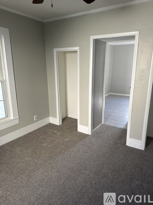 A room with grey carpet and three open doors.