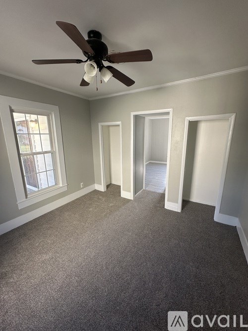 A room with a ceiling fan and carpeted floor.