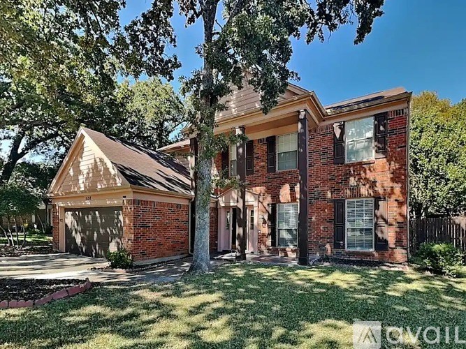 A red brick house with a tree in front.
