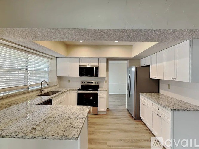 A kitchen with white cabinets and a granite countertop.