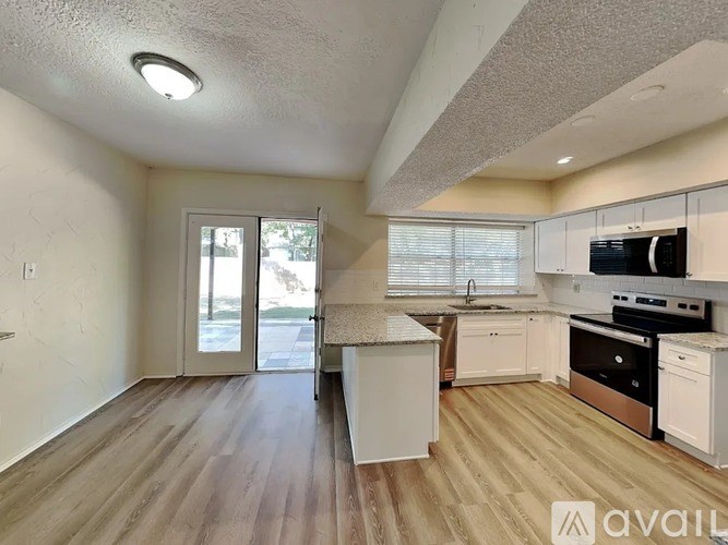 A kitchen with white appliances and wooden floors is available for rent.