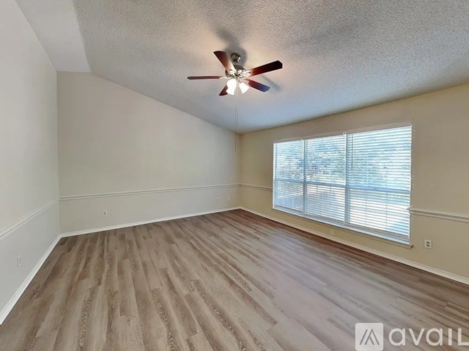 A room with a ceiling fan and wooden flooring.