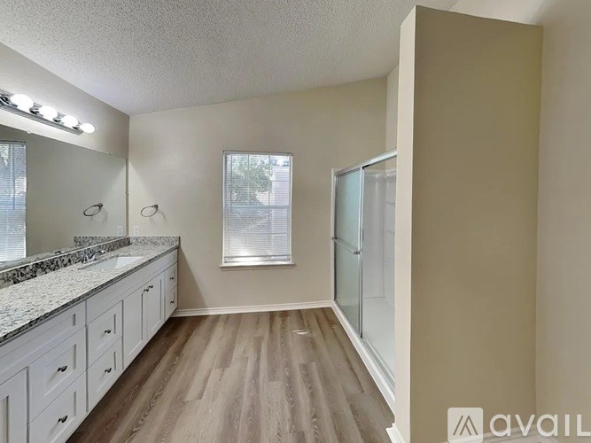 A spacious bathroom with a marble countertop and wooden flooring.