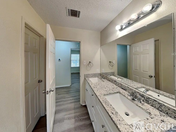 A bathroom with a sink, mirror, and lighting fixture.