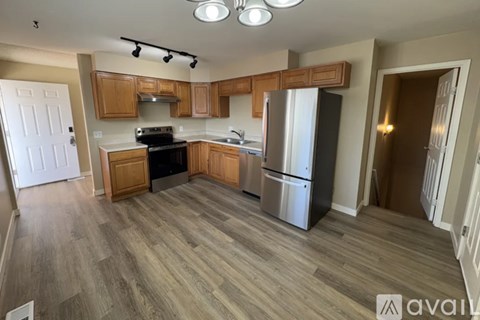 A kitchen with wooden cabinets and a stainless steel refrigerator.