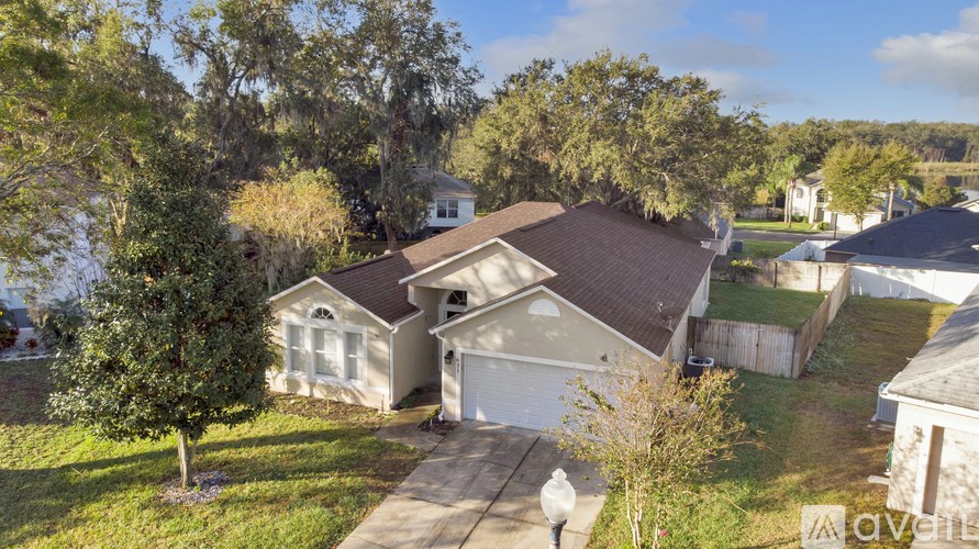 A house with a brown roof and a white garage door is surrounded by trees.