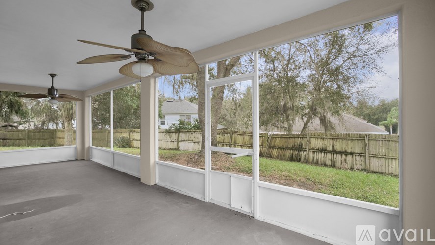 A sunny day in a spacious room with a ceiling fan and large windows.