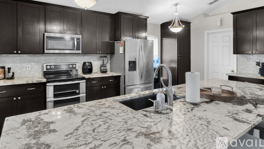 A kitchen with a marble countertop and dark wood cabinets.