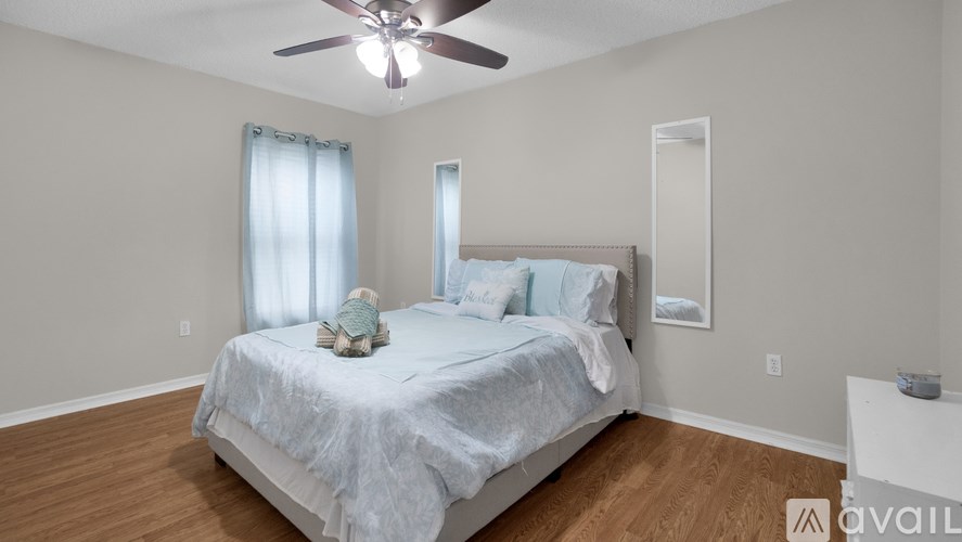 A bedroom with a bed, a ceiling fan, and a window with curtains.