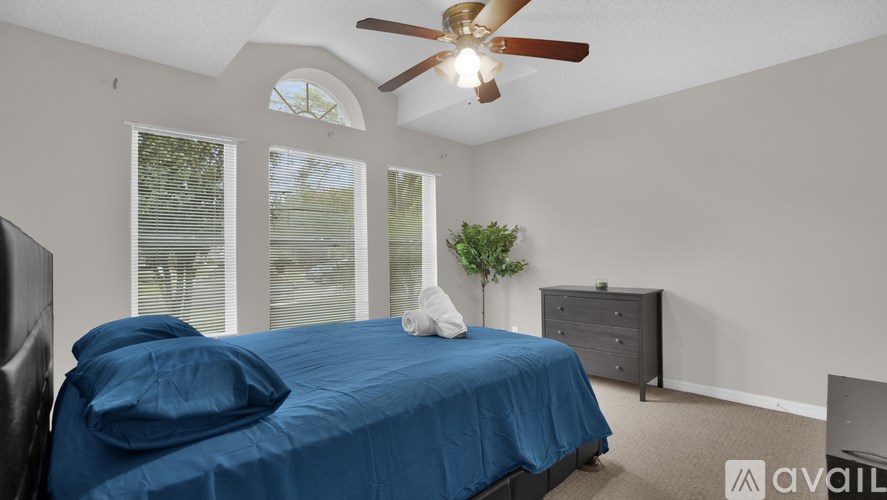 A bedroom with a bed, dresser, and ceiling fan.