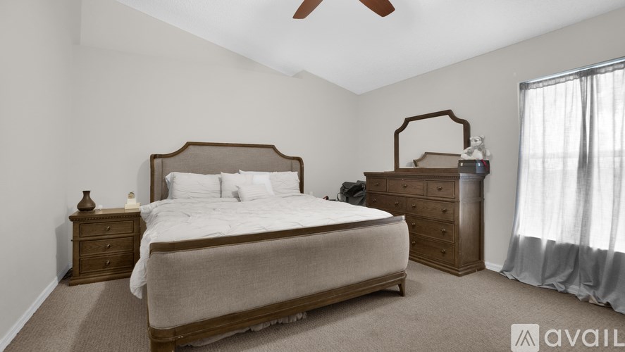 A bedroom with a large bed, a nightstand, and a dresser.