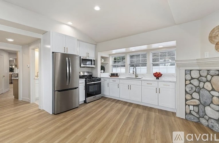 A modern kitchen with wooden floors and stainless steel appliances.