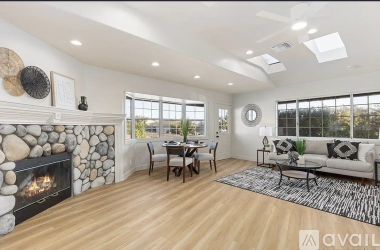 A modern living room with a stone fireplace and a dining area.