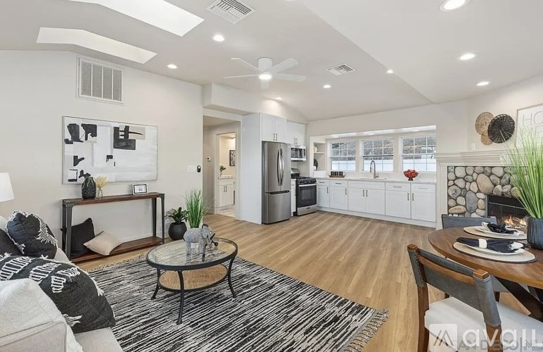 A modern living room with a black and white rug, a coffee table, and a kitchen in the background.