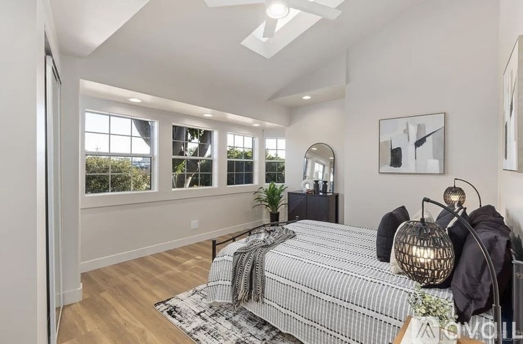 A bedroom with a bed, a mirror, and a ceiling fan.