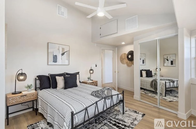 A bedroom with a large bed and a mirrored closet door.