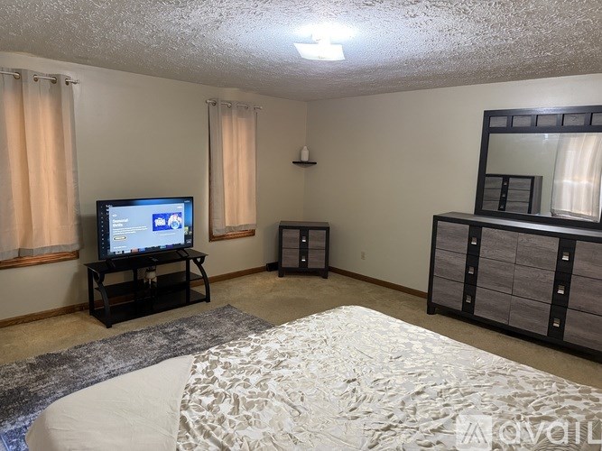 A bedroom with a bed, dresser, and television.