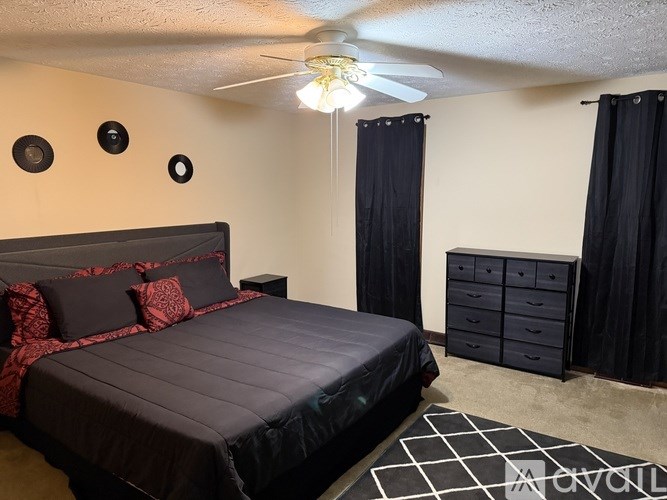 A bedroom with a black bedspread and red pillows.