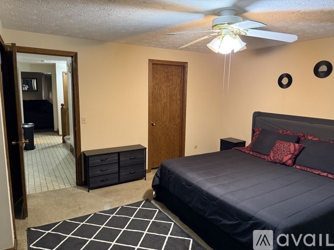 A bedroom with a bed, dresser, and ceiling fan.