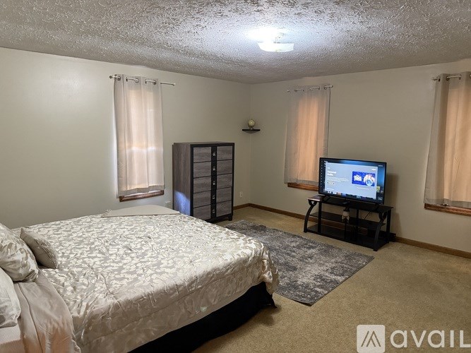 A bedroom with a bed, a television, and a cabinet.