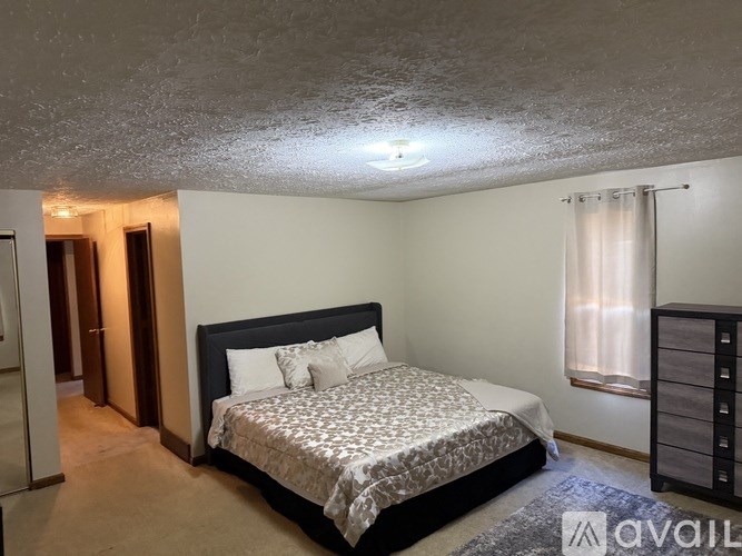 A bedroom with a large bed and a window with curtains.