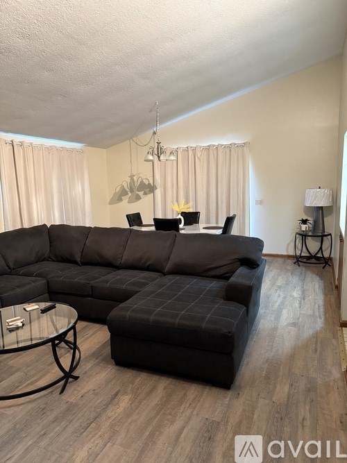 A living room with a black sofa and a glass coffee table.