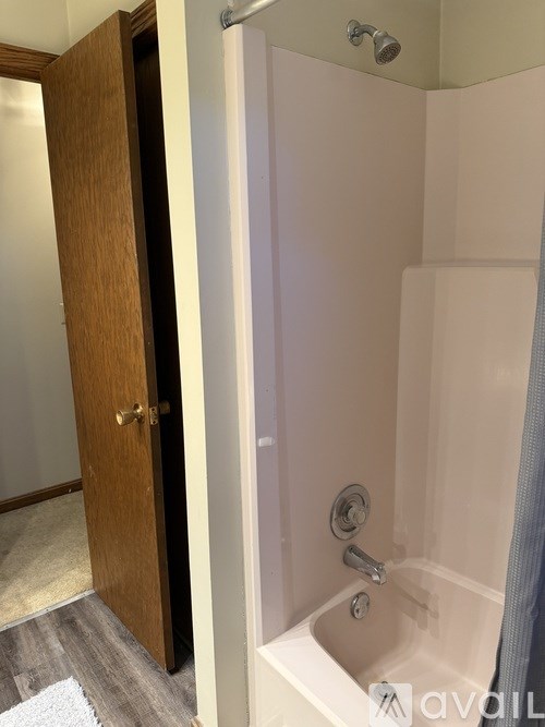 A bathroom with a white tub and a wooden door.