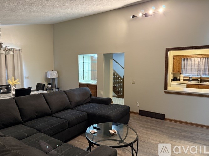 A black sofa in a living room with a glass table in front of it.