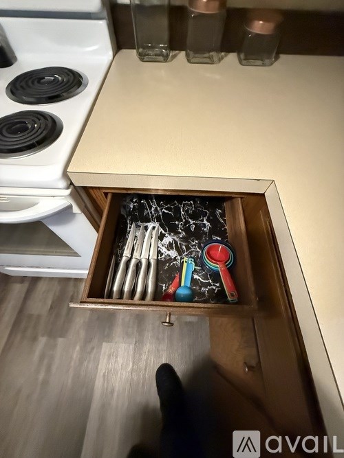 A drawer in a kitchen cabinet with a chalkboard and measuring spoons.
