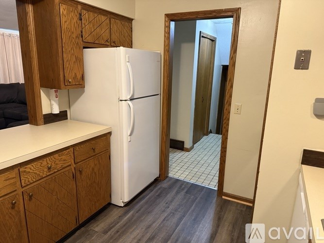 A kitchen with a white refrigerator and wooden cabinets.