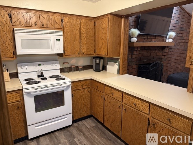 A kitchen with wooden cabinets and a white stove top oven.