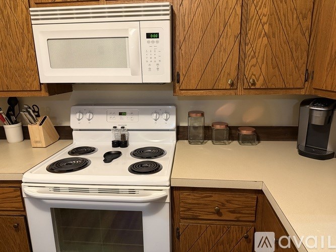 A white stove top oven with four burners and a white microwave above it.