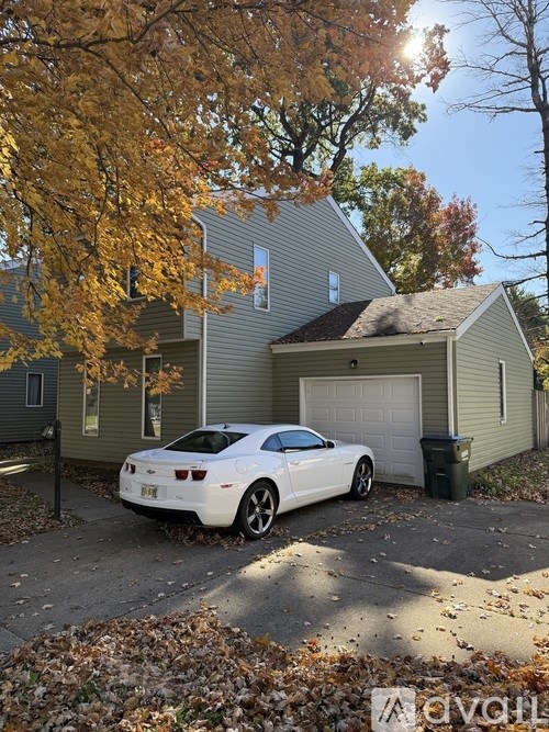 A white car is parked in front of a house.
