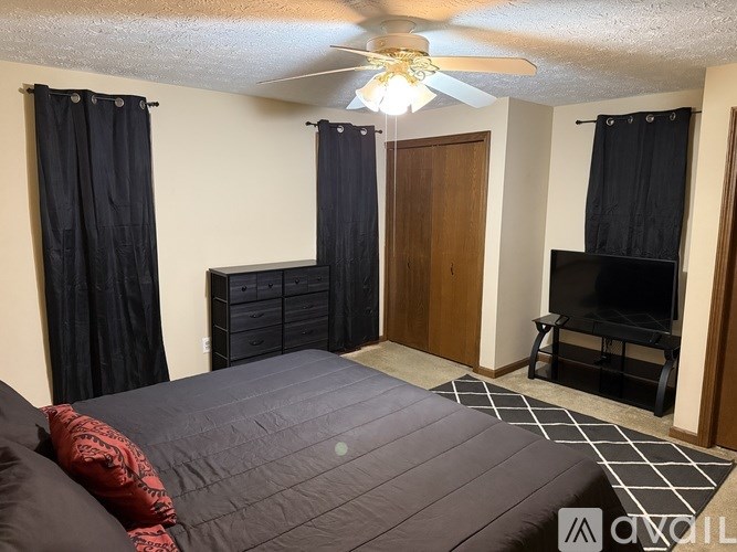 A bedroom with a bed, dresser, and television.