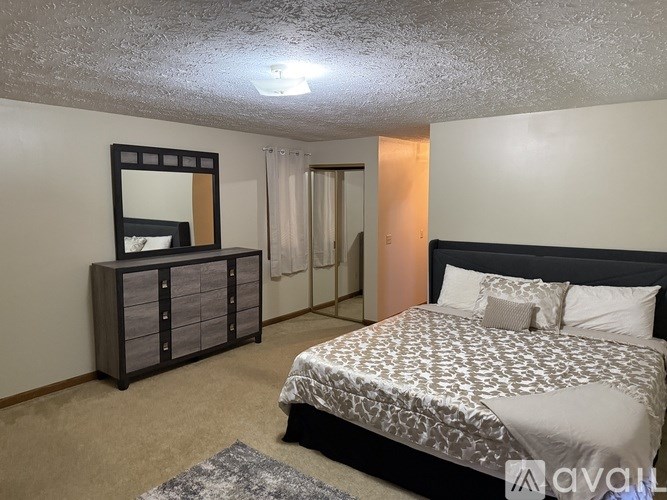 A bedroom with a bed, dresser, and mirror.