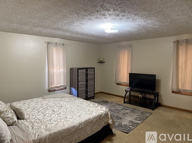 A bedroom with a bed, a television, and a cabinet.