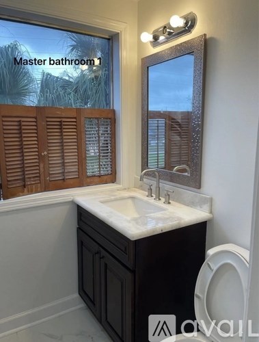 A bathroom with a sink, mirror, and a window with wooden shutters.