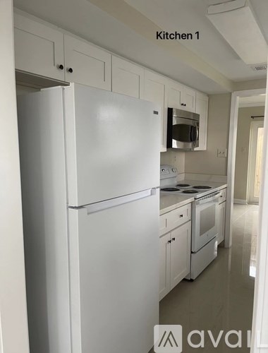 A white refrigerator in a kitchen with white cabinets.