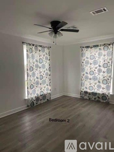Bedroom 2 has a ceiling fan and patterned curtains.