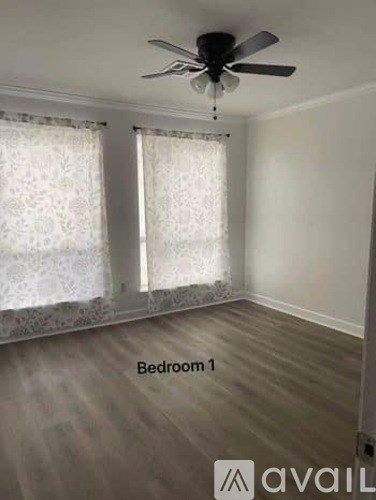 Bedroom 1 has a ceiling fan and lace curtains.