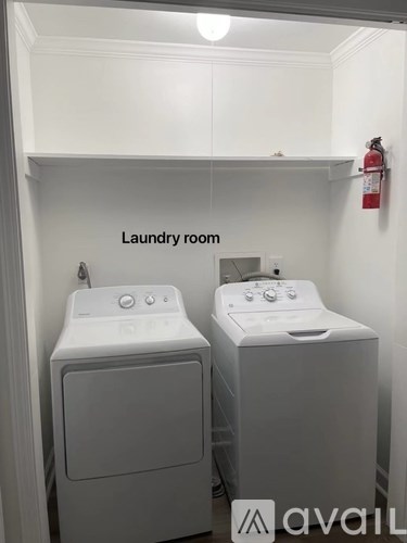 A laundry room with two washing machines and a fire extinguisher.