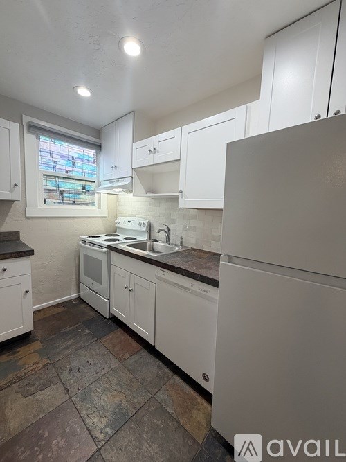 A kitchen with white cabinets and a tiled floor.