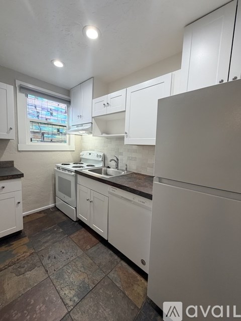 A kitchen with white cabinets and a tiled floor.