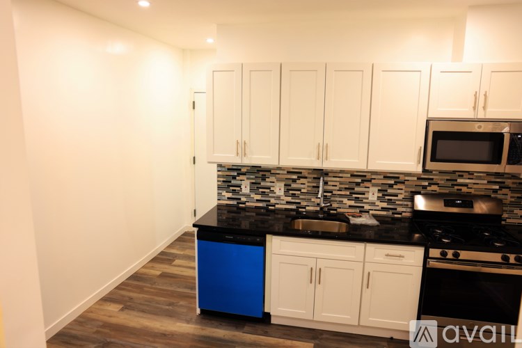 A kitchen with white cabinets and a black countertop.