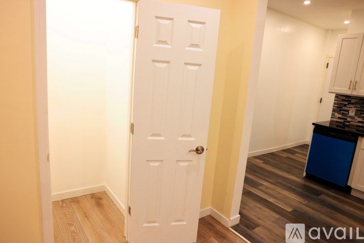 A white door with a gold handle is in a room with wooden floors.